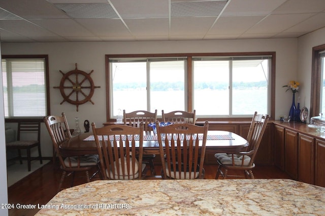 dining area featuring a paneled ceiling, dark wood-type flooring, and a healthy amount of sunlight