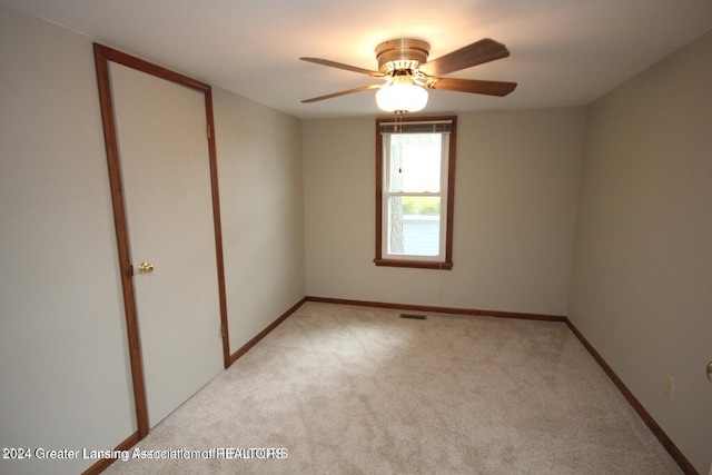 spare room with ceiling fan and light carpet