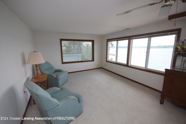 sitting room with carpet, a water view, and ceiling fan