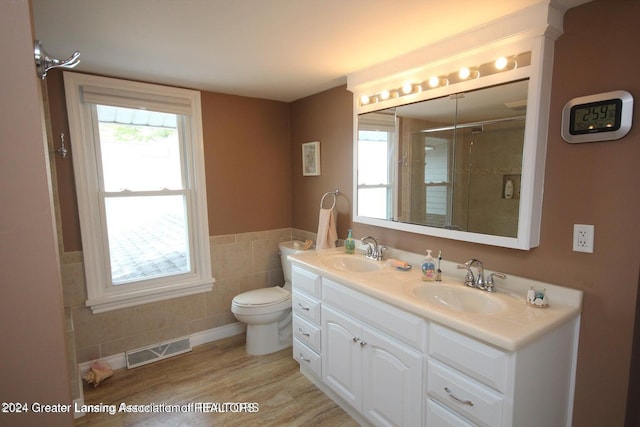 bathroom featuring vanity, a shower, hardwood / wood-style flooring, tile walls, and toilet