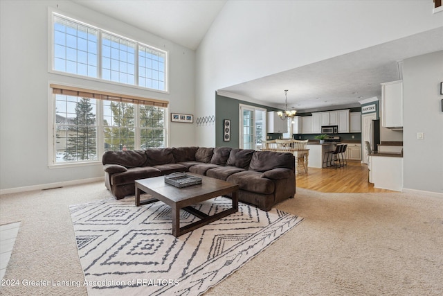 living room featuring light carpet, crown molding, a towering ceiling, and a notable chandelier