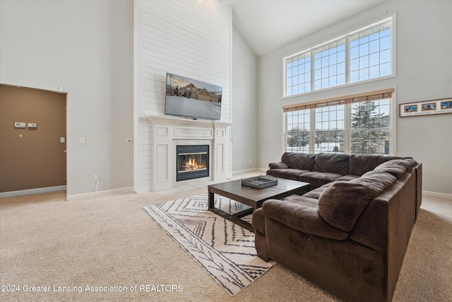 living room featuring light carpet, a fireplace, and a high ceiling