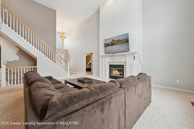 living room featuring carpet, a large fireplace, high vaulted ceiling, and a chandelier