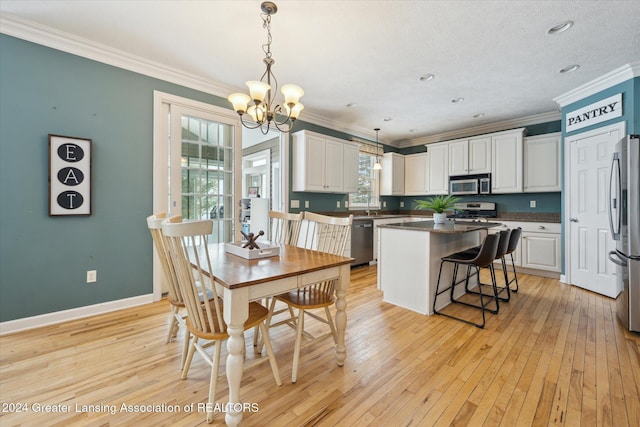 dining area featuring light wood-type flooring, an inviting chandelier, crown molding, and sink