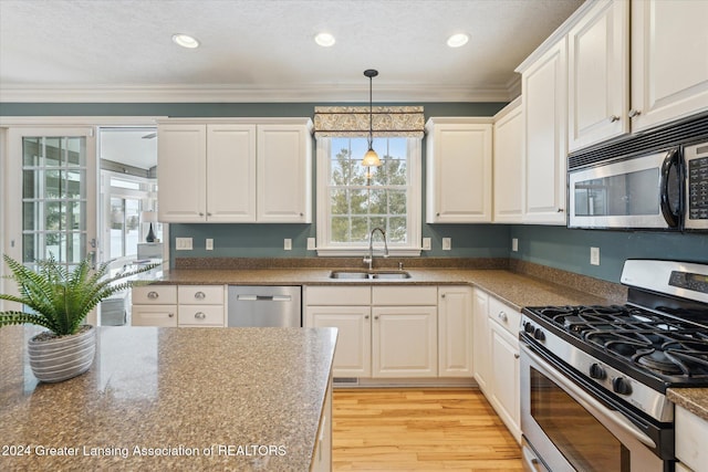 kitchen with crown molding, sink, hanging light fixtures, white cabinetry, and stainless steel appliances