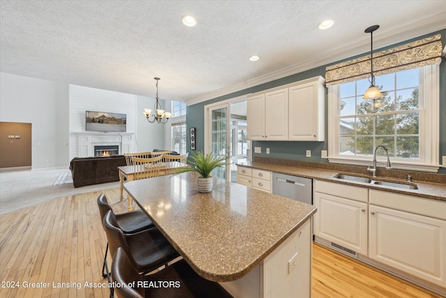 kitchen with a kitchen bar, stainless steel dishwasher, sink, pendant lighting, and a center island