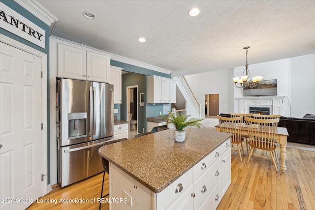 kitchen with a center island, white cabinets, ornamental molding, stainless steel fridge with ice dispenser, and a breakfast bar area