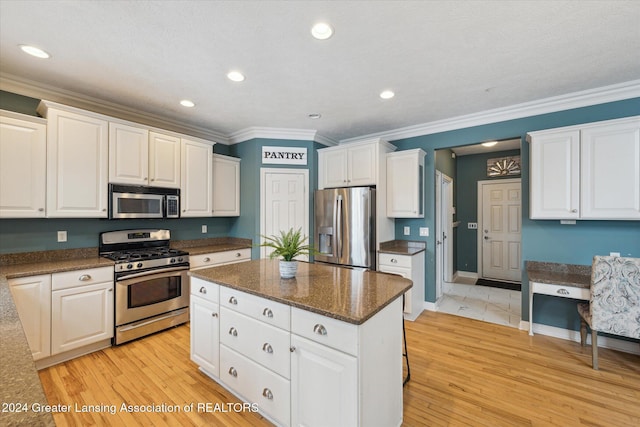 kitchen featuring white cabinets, a center island, ornamental molding, and stainless steel appliances