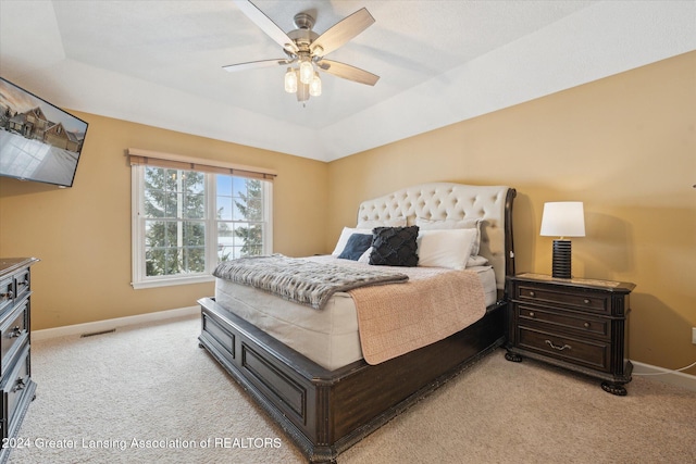 bedroom featuring ceiling fan, a raised ceiling, light carpet, and vaulted ceiling