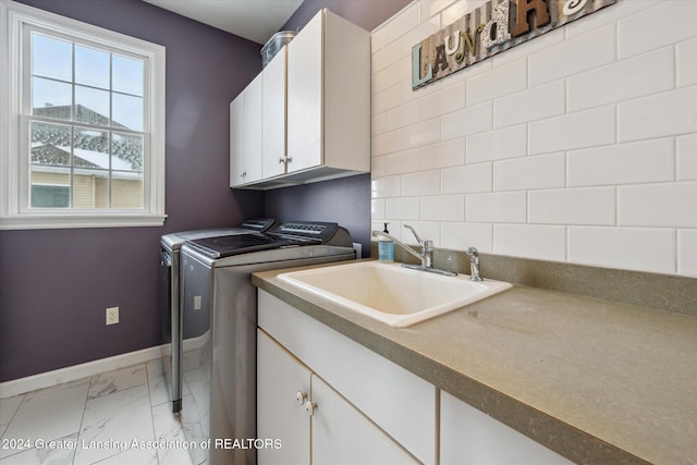 clothes washing area featuring washer and clothes dryer, cabinets, and sink