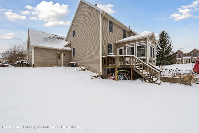 snow covered property with central air condition unit and a wooden deck