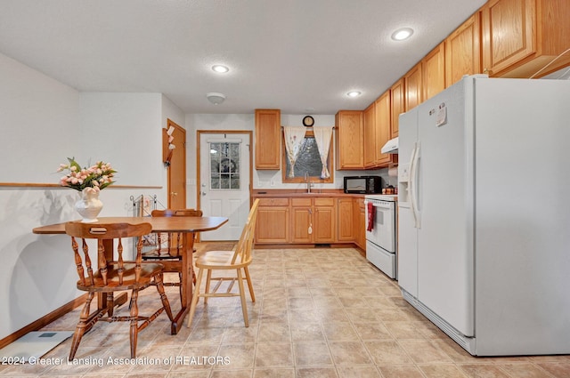 kitchen with light brown cabinets, stove, white refrigerator with ice dispenser, and sink