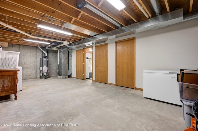 basement with heating unit, water heater, and refrigerator