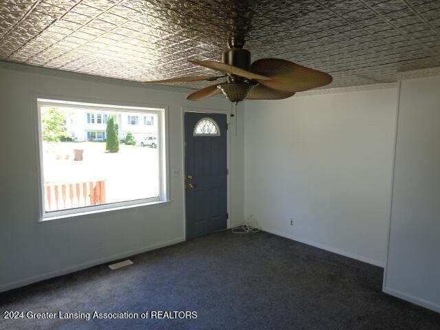 entrance foyer featuring dark colored carpet, ceiling fan, and plenty of natural light