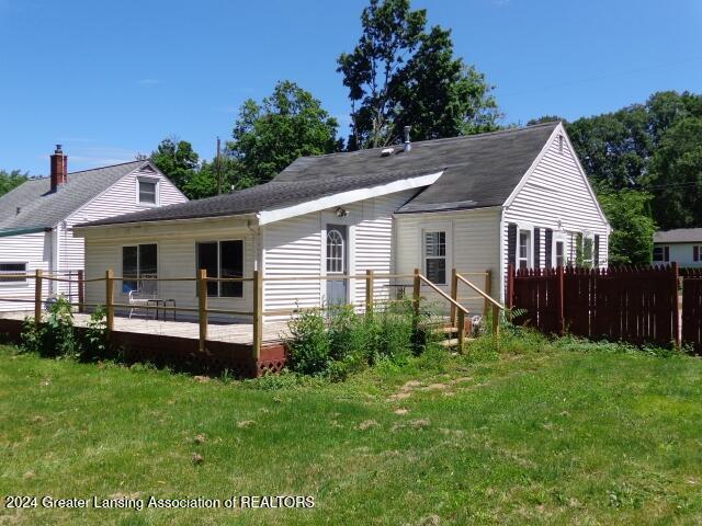 back of house featuring a lawn and a deck