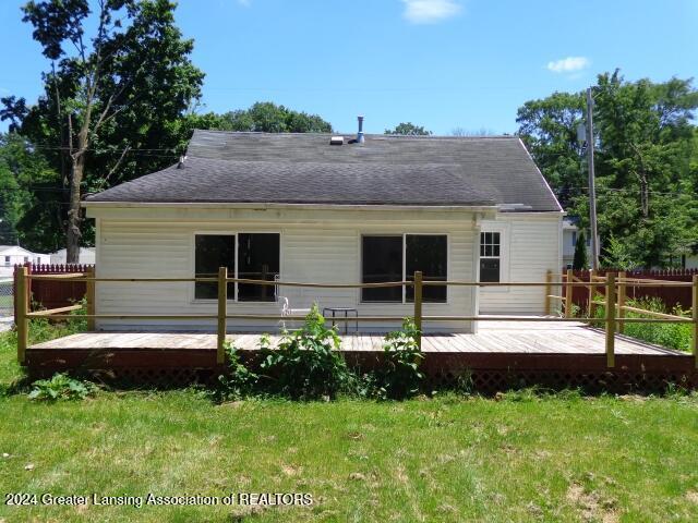 back of property with a wooden deck and a yard