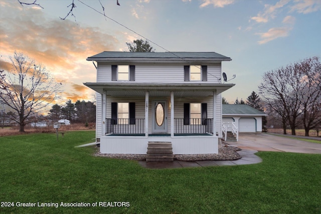 view of front of house featuring a lawn, a porch, a garage, and an outbuilding