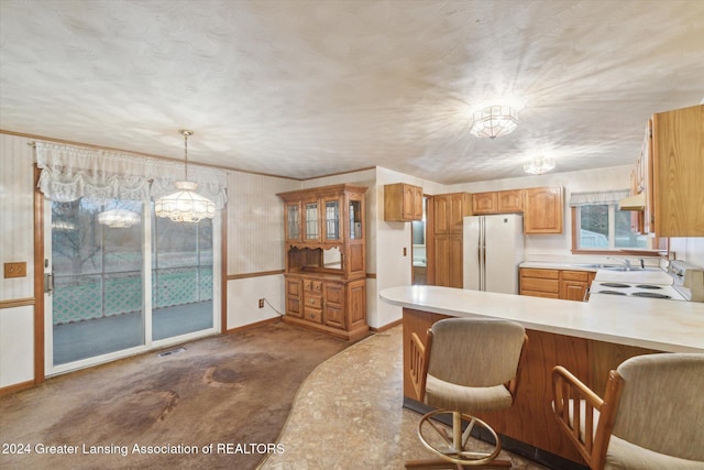 kitchen with a breakfast bar, white appliances, decorative light fixtures, a notable chandelier, and kitchen peninsula