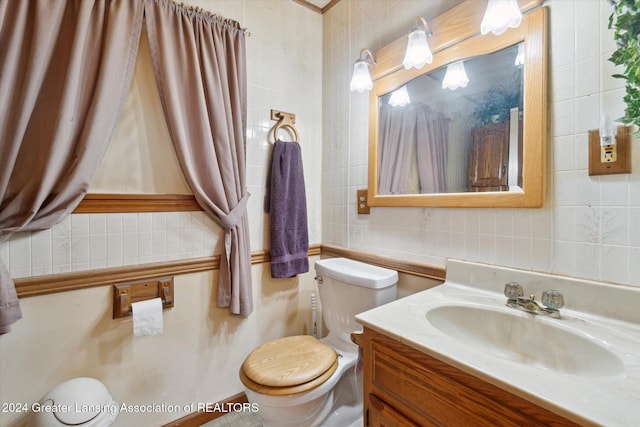 bathroom with vanity, tile walls, and toilet