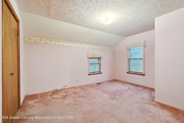 carpeted spare room featuring a textured ceiling and vaulted ceiling