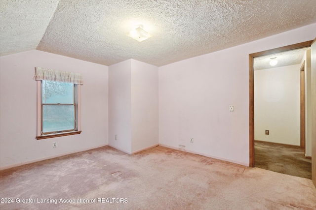 carpeted empty room with a textured ceiling and lofted ceiling