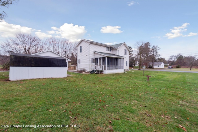 back of house with a sunroom, a shed, and a yard