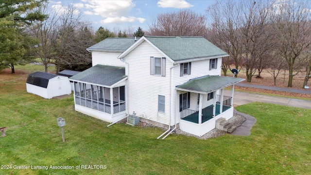 view of side of home with a lawn, a sunroom, covered porch, and central AC unit