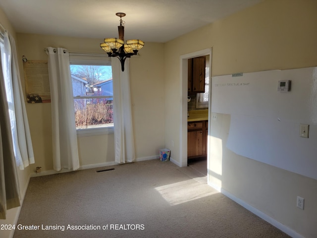 empty room featuring light carpet and a notable chandelier