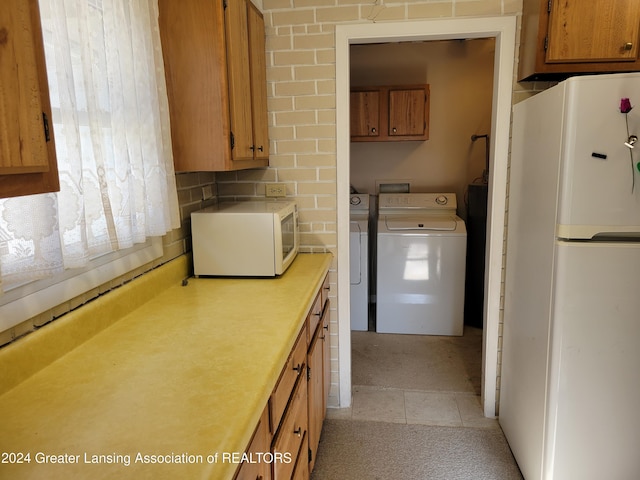 kitchen featuring washer and clothes dryer, white appliances, light tile patterned floors, and tasteful backsplash