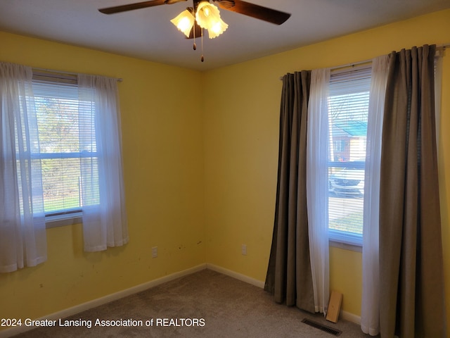 carpeted spare room featuring plenty of natural light and ceiling fan