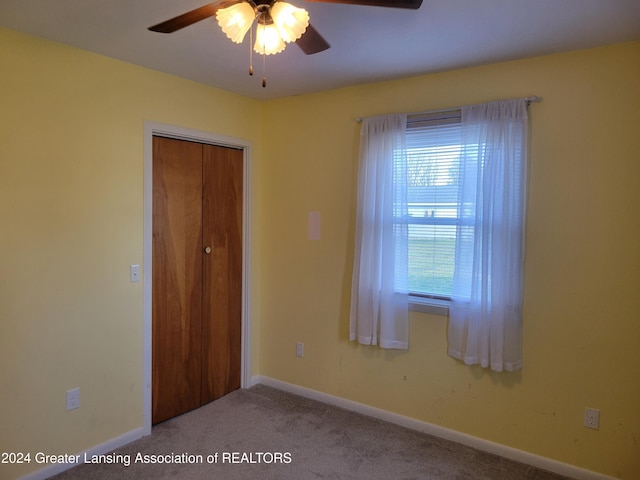 carpeted spare room with ceiling fan