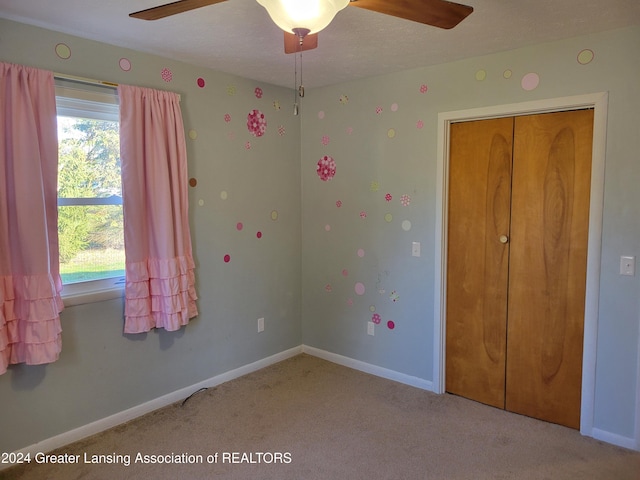 unfurnished bedroom with ceiling fan, light carpet, and a closet