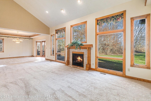 unfurnished living room featuring carpet, a tiled fireplace, high vaulted ceiling, and a chandelier