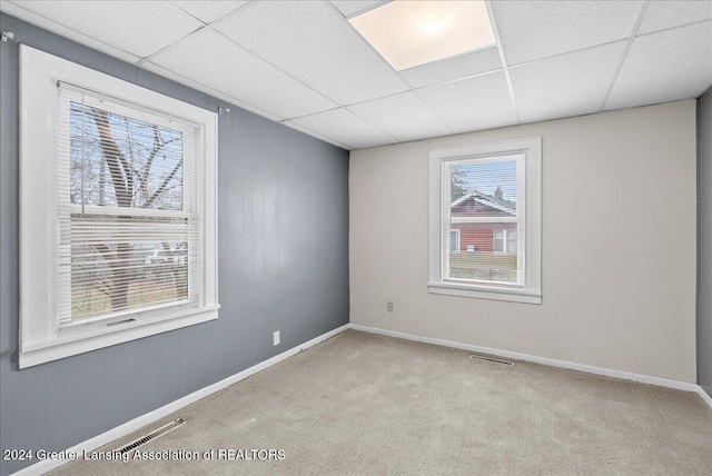 carpeted empty room featuring a drop ceiling