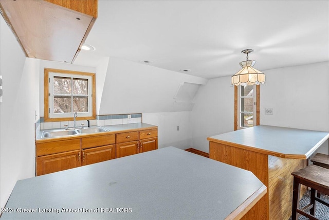 kitchen with sink, hanging light fixtures, kitchen peninsula, lofted ceiling, and a breakfast bar area