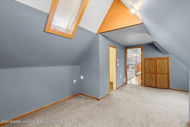 additional living space with light colored carpet and vaulted ceiling