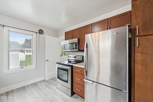 336 S Waverly Rd, Lansing, MI 48917 - kitchen featuring stainless steel appliances, light wood finished floors, baseboards, light countertops, and brown cabinets