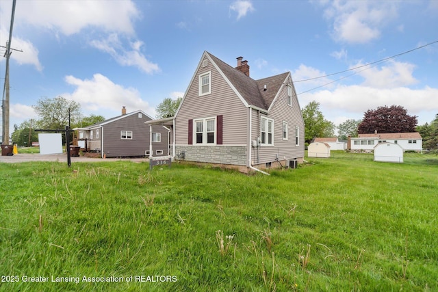 336 S Waverly Rd, Lansing, MI 48917 - rear view of property featuring a chimney, a shingled roof, central AC unit, and a yard