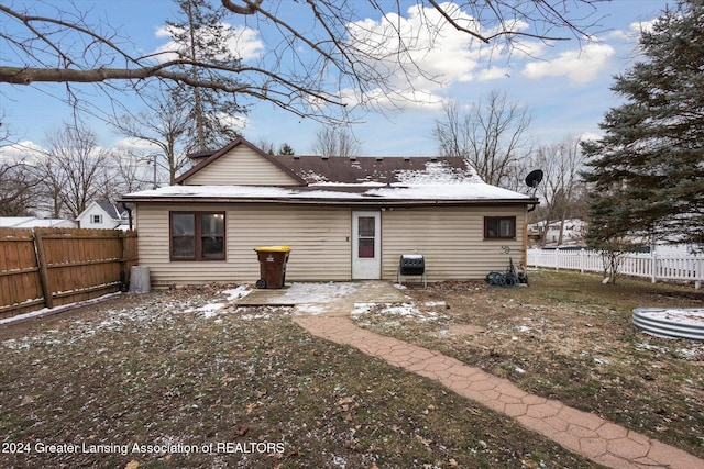 snow covered back of property with a patio and a lawn