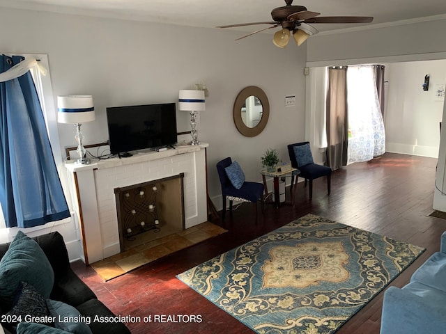 living room featuring hardwood / wood-style flooring, ceiling fan, ornamental molding, and a fireplace