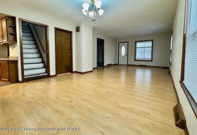 unfurnished living room with a chandelier and light hardwood / wood-style flooring