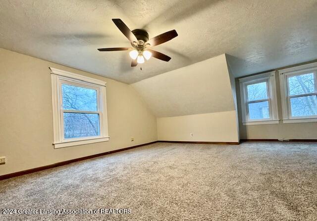 additional living space featuring a textured ceiling, ceiling fan, carpet, and lofted ceiling