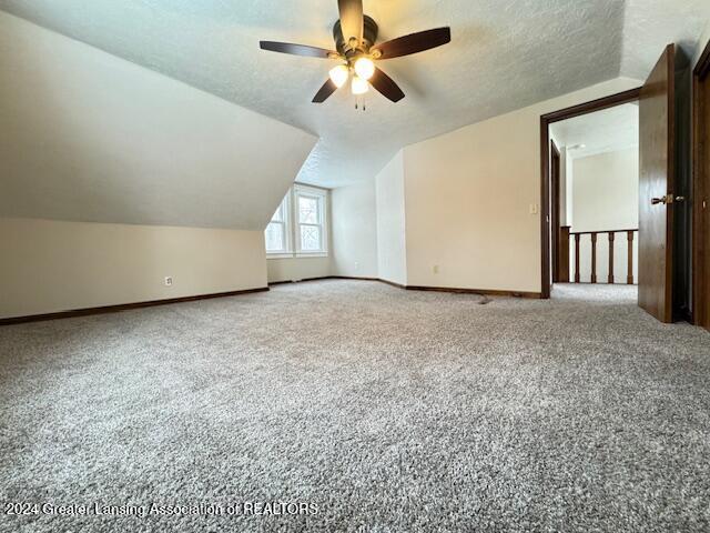 bonus room with carpet, a textured ceiling, ceiling fan, and lofted ceiling