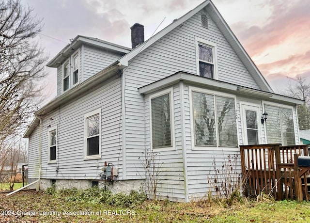 back house at dusk featuring a wooden deck