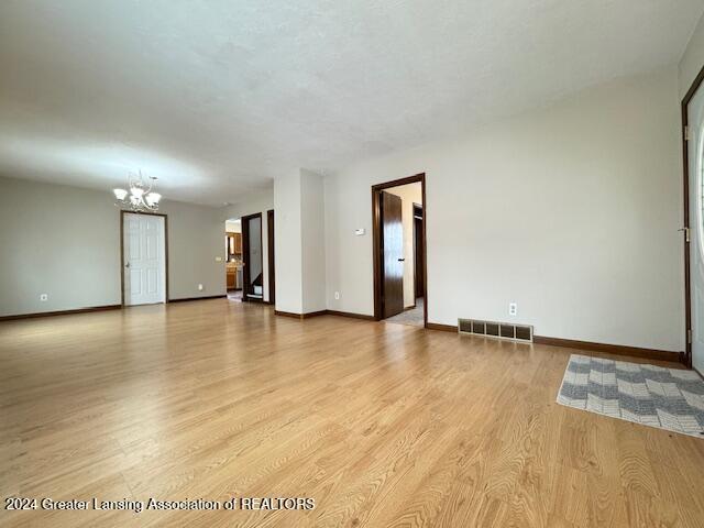 unfurnished room featuring light hardwood / wood-style flooring and an inviting chandelier