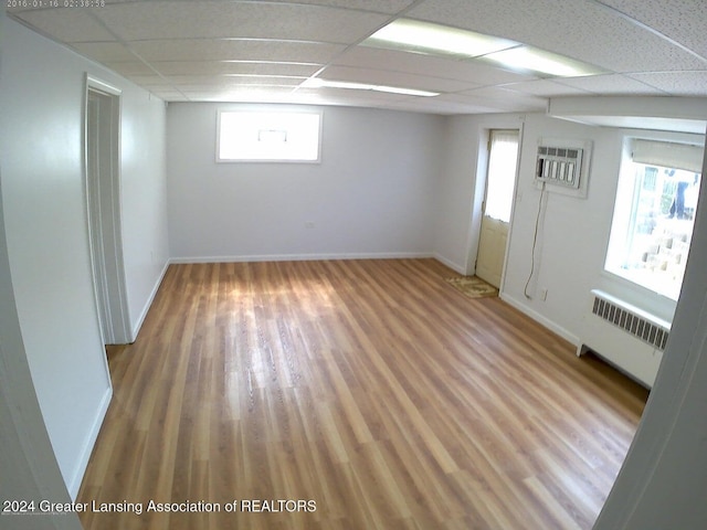 unfurnished room with a paneled ceiling, plenty of natural light, wood-type flooring, and radiator