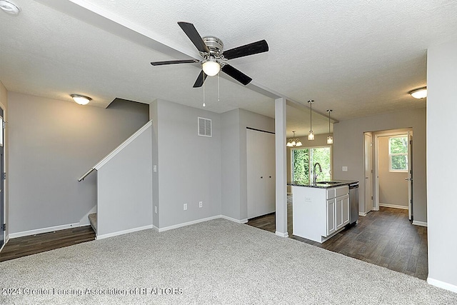 interior space featuring a textured ceiling, dark carpet, ceiling fan, and sink