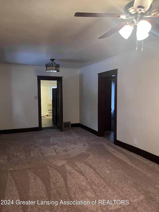 empty room featuring carpet, ceiling fan, and ornamental molding