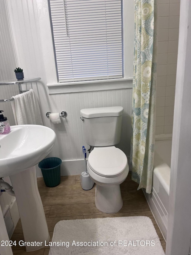 bathroom featuring hardwood / wood-style flooring, toilet, and shower / tub combo with curtain