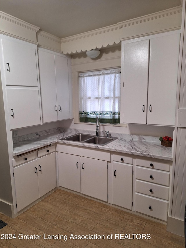 kitchen featuring white cabinets, crown molding, sink, and light hardwood / wood-style flooring